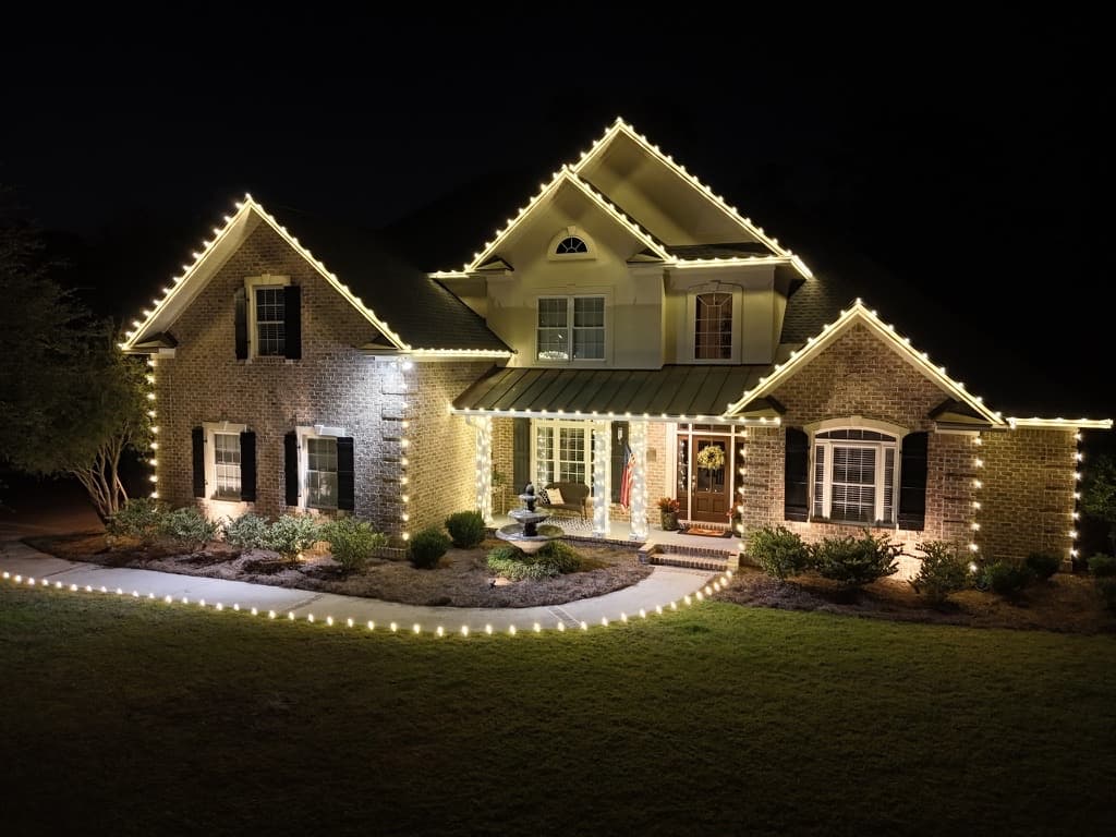 Two-story brick home with warm-white roofline and pathway lighting