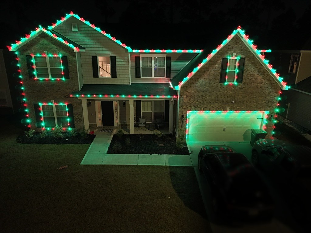 Two-story Pooler-area home outlined in red and green lights with window frames and garage lines picked out